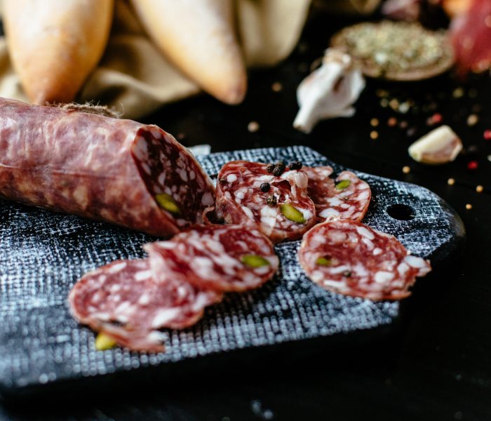 Delicious sliced Italian sausage with pistachios and spice on black cutting board